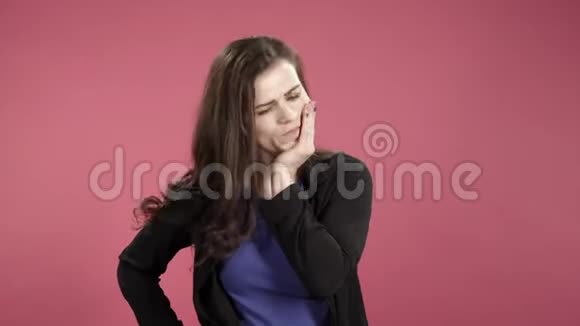 牙痛粉红色背景下牙齿疼痛的年轻女人视频的预览图