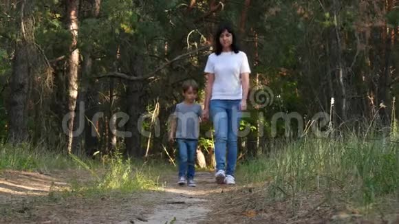 家庭母婴在森林或公园散步享受大自然幸福的母亲牵着儿子手走了下来视频的预览图