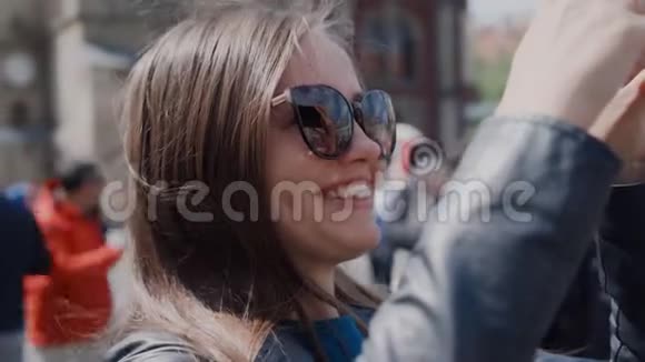 微笑女孩用手机拍照城市旅游景点视频的预览图