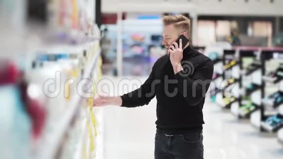 年轻的胡子男打电话在化妆品店挑选产品视频的预览图