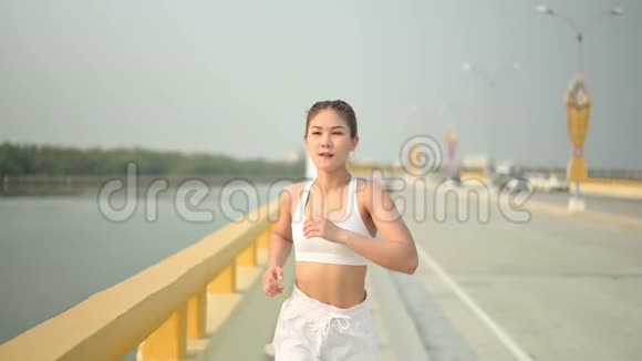 慢动作运动员女子在海滩路跑步亚洲女跑运动员夏季耐力训练视频的预览图