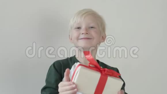 一个孩子拿出一个包装精美的盒子把礼物放进相机里视频的预览图