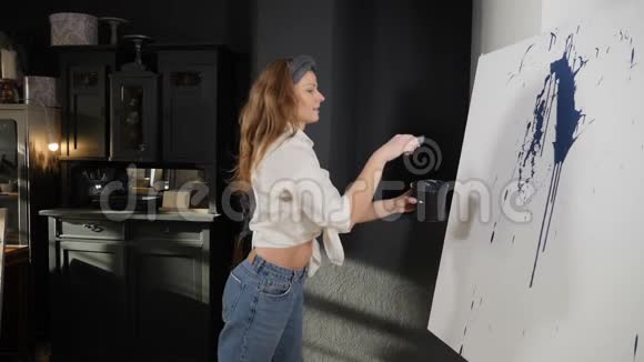 女画家用画笔在白色画布上泼洒蓝色丙烯酸颜料慢动作刷喷涂液体漆视频的预览图