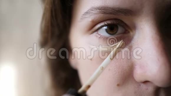 遮瑕膏在女性眼部特写下的应用一个白种人的女孩正在申请一个米色的丁丁基金会视频的预览图