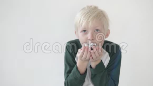 小男孩在一个白色背景的工作室里吹纸屑视频的预览图