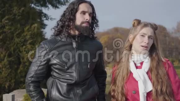 无忧无虑的中东男人和高加索女人站在秋天公园里谈话的肖像快乐的金发女友视频的预览图