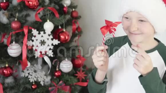 一个戴圣诞老人帽子的男孩装饰圣诞树视频的预览图
