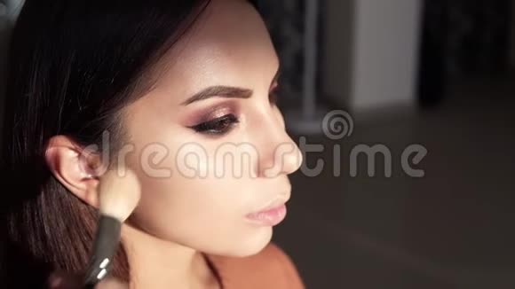 化妆师应用高亮稍微使用一个大刷子艺术家正在应用于模特的面部特写视频的预览图