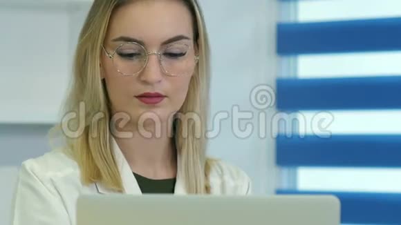 女医生戴眼镜在前台用笔记本电脑工作视频的预览图