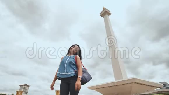 年轻的印度尼西亚女孩在印度尼西亚国家纪念碑的背景上摆姿势视频的预览图