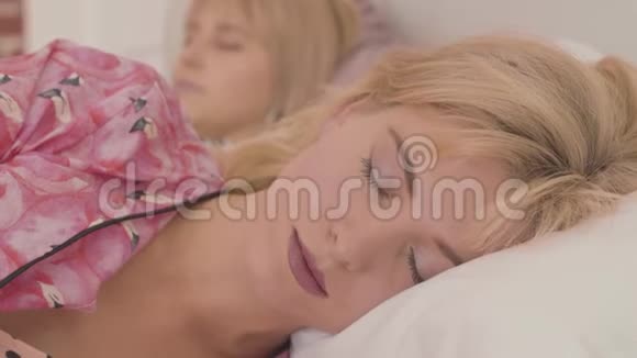 一位美丽的金发白种人女人正在睡觉她的朋友正在接近闹钟闹钟显示她点视频的预览图