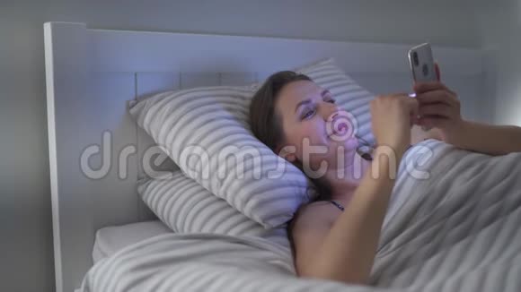 女人躺在床上用智能手机移动成瘾或失眠的概念视频的预览图