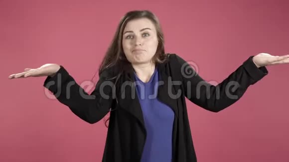 困惑的年轻女子怀疑和耸肩在粉红色的背景上视频的预览图
