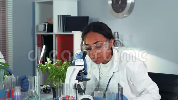 多种族女科学家安全眼镜使用同事的化学液体烧瓶在她的实验视频的预览图