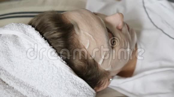 一个穿毛巾的年轻女人把圆圆的黄瓜放在眼睛上有机美容护理视频的预览图