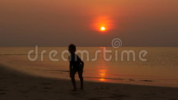 小女孩跳着跳着高兴傍晚日落时分在海滨拍摄视频的预览图