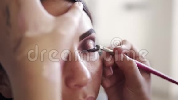 特写的过程女性化妆艺术家轻轻应用黑色眼线使用特定的刷子完美晚上做视频的预览图