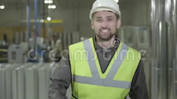 快乐的白种人留着胡子戴着保护头盔在钢金属管道的背景下滑稽地跳舞雇员视频的预览图