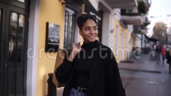 一个迷人的混血女孩带着一个棕色的小袋子走在街上微笑的肖像快乐的年轻女子视频的预览图