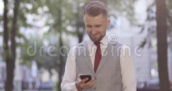 一个穿西装的商人正站在公园里在手机上读着一条信息视频的预览图
