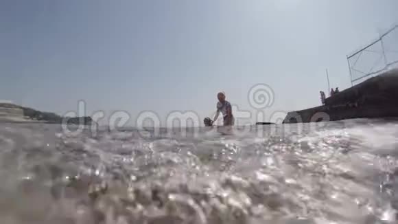 一个女人带着一个年轻的女儿在海里游泳在框架中你可以看到海底和波浪在截面上视频的预览图