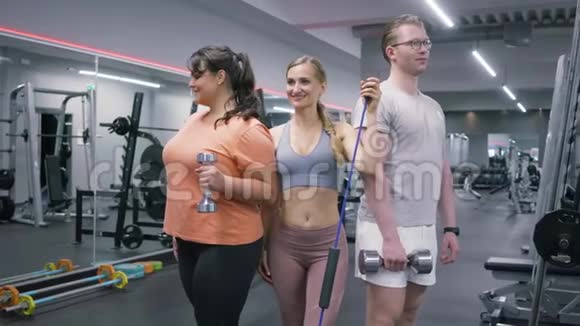 两个身材匀称的女人和一个在健身房摆哑铃的男人视频的预览图