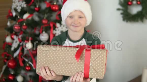一个戴着圣诞老人帽子的孩子会送一份漂亮的礼物视频的预览图