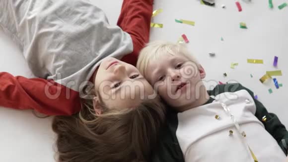 男孩和女孩躺在地上的纸屑和笑声视频的预览图