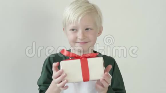 金发男孩拿出一个包装精美的礼物送给相机视频的预览图