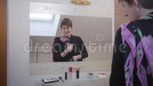成熟的白种人高级妇女在浴室的大镜子前看着两条围巾优雅的女商人视频的预览图