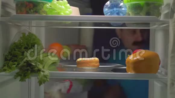 一个留胡子晚上不节食的滑稽男人从冰箱里拿出一个甜甜圈视频的预览图