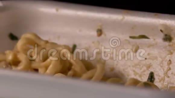 一个有胃口的饥饿男人用容器里的塑料叉子吃面条特写视频的预览图