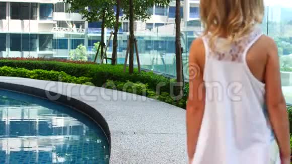 一个穿着白色连衣裙的女孩慢慢地走着视频的预览图