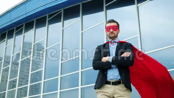 穿着红色超级英雄斗篷和面具的严肃办公室工作人员站在外面的肖像视频的预览图