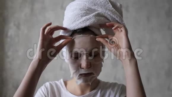 一个年轻的女人从她的脸上取出一个保湿面膜并将其重新应用到她的脖子上美容护肤美容视频的预览图