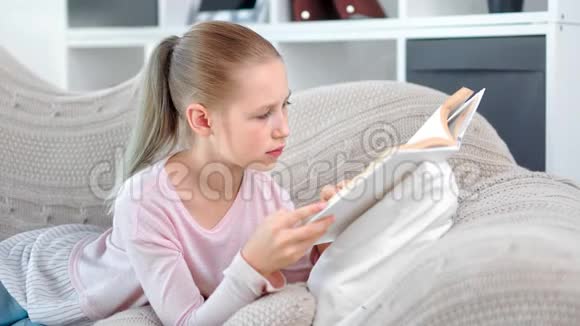 可爱专注的小学生女孩自信地看书翻页在家放松视频的预览图
