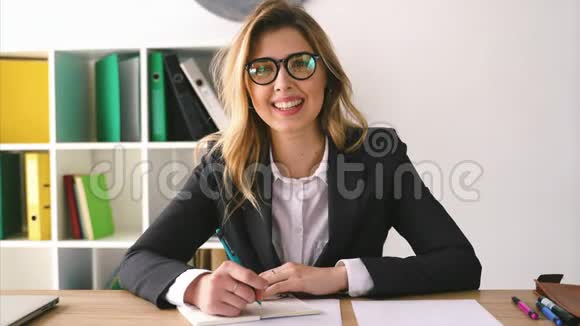 微笑商务女性坐在办公桌上手里拿着一支笔拿着文件签合同视频的预览图