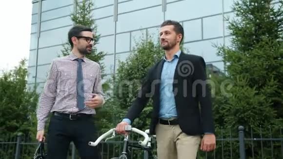 喜欢骑自行车的商人从工作中步行办公大楼交谈视频的预览图