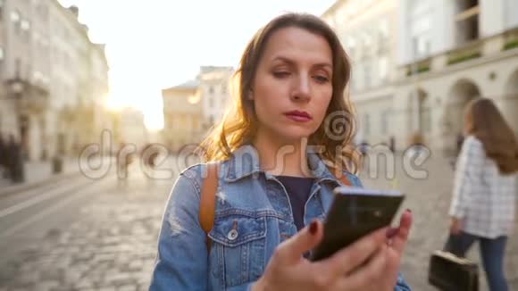 女人站在老城区广场的中央用智能手机拍摄日落美景视频的预览图