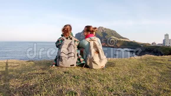 两个年轻女子背包客坐在悬崖边上视频的预览图