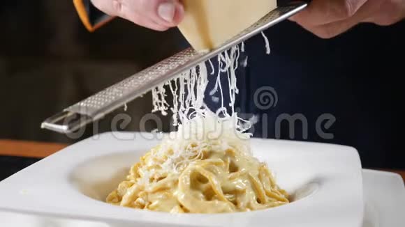 食物录像拍摄慢镜头奶酪正被烤在刚煮熟的意大利面食上厨师光栅视频的预览图