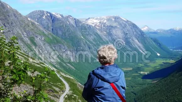 在山区度假的高级妇女在挪威欣赏绿谷和山景的成熟女士视频的预览图