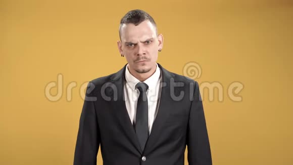一个愤怒的商人用双臂交叉在黄色背景下的肖像视频的预览图