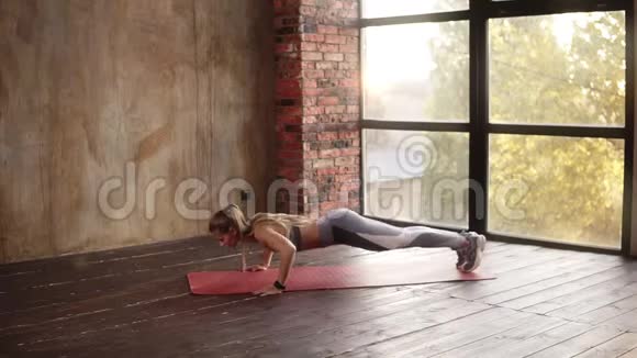 健身年轻女子在红色运动垫上做俯卧撑健康的年轻女性在空健身工作室工作金发美女视频的预览图