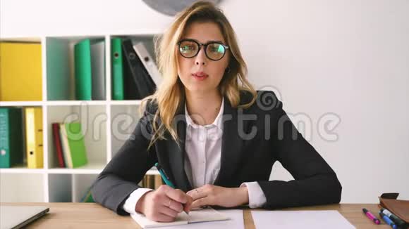 微笑商务女性坐在办公桌上手里拿着一支笔拿着文件签合同视频的预览图