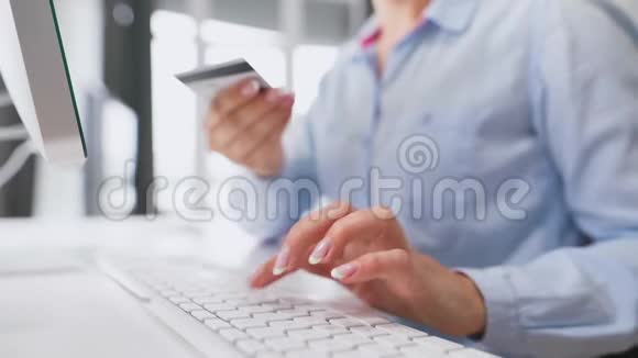 女性手在电脑键盘上输入信用卡号码女人在网上购买在线支付服务视频的预览图