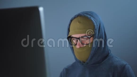 男性黑客戴着面具戴着眼镜在黑暗的办公室里在电脑上工作网络犯罪概念视频的预览图