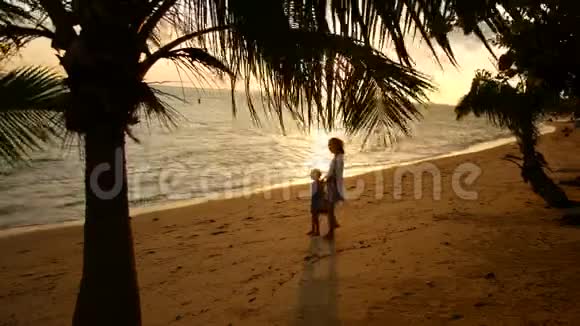 母亲和女儿在日落时沿着海岸散步视频的预览图