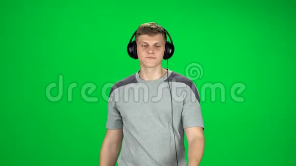 戴着大耳机的人去录音室听音乐在绿色屏幕上跳舞视频的预览图