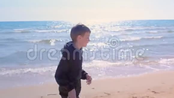 小男孩正在海边慢跑沙滩小跑步户外运动侧面观看视频的预览图